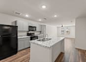 Thumbnail 12 of 39 - A kitchen with a black refrigerator and white countertops.