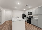 Thumbnail 23 of 39 - A kitchen with a white marble island and dark wood floors.