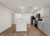 Thumbnail 25 of 39 - A kitchen with a white island and black appliances.