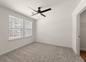 Thumbnail 26 of 39 - A room with a ceiling fan and carpeted floor.