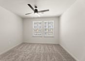 Thumbnail 14 of 39 - A room with a ceiling fan and carpeted floor.