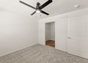 Thumbnail 19 of 39 - A room with a ceiling fan and a door leading to another room.