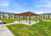 Thumbnail 9 of 45 - A wooden pavilion is surrounded by grass and concrete walkways.