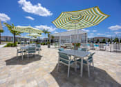 Thumbnail 60 of 83 - A patio with a table and chairs under a striped umbrella.