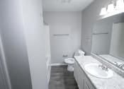 Thumbnail 11 of 11 - Bathroom with a sink toilet and mirror at Canterbury House apartments in Logansport, Indiana
