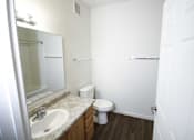 Thumbnail 26 of 28 - A white bathroom with a toilet, sink, and mirror.