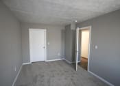Thumbnail 15 of 17 - Empty bedroom with a white door and gray walls at Canterbury House apartments in Tipton, Indiana