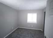 Thumbnail 8 of 11 - Empty bedroom with a window and a door at Canterbury House apartments in Logansport, Indiana
