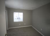 Thumbnail 16 of 17 - Empty bedroom with a window and a door at Canterbury House apartments in Tipton, Indiana