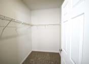 Thumbnail 27 of 28 - A white closet with a carpeted floor and a white door.