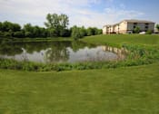 Thumbnail 2 of 15 - a small pond in front of apartment buildings at Canterbury Apartments in Kalamazoo, MI