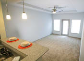 Thumbnail 18 of 31 - Living room view with a counter, ceiling fan, two windows and a door at Mosaic Apartments in Avon, Indiana