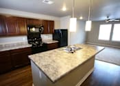 Thumbnail 8 of 25 - A kitchen with a granite countertop and wooden cabinets.