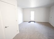 Thumbnail 6 of 18 - A white door is open to a room with a carpeted floor and white walls.