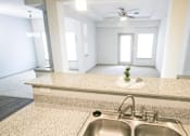 Thumbnail 20 of 31 - View from kitchen counter with sink with a living room with a door and window in the background at Mosaic Apartments in Avon, Indiana