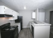 Thumbnail 12 of 17 - Kitchen with white cabinets and black appliances at Canterbury House apartments in Tipton, Indiana