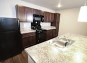 Thumbnail 14 of 25 - A kitchen with a black fridge, microwave, and oven.