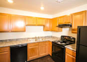 Thumbnail 2 of 18 - A kitchen with black appliances and wooden cabinets.