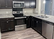 Thumbnail 21 of 31 - Kitchen with stove and sink at Promenade Luxury apartments in Beaumont, Texas