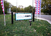 Thumbnail 24 of 25 - A sign that says Overlook Pointe Apartments in front of some flags.
