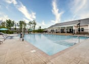 Thumbnail 6 of 42 - Swimming pool at Aurora Luxury Apartments with chaise lounge chairs and a building in the background