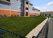 Thumbnail 15 of 19 - A grassy area in front of a building with a fence on the right side.