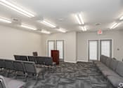 Thumbnail 9 of 21 - A conference room with grey chairs and a podium.