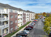 Thumbnail 5 of 21 - A row of apartment buildings with cars parked in front.