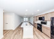 Thumbnail 9 of 35 - A kitchen with a white island in the middle of the room.
