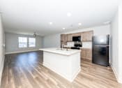 Thumbnail 1 of 35 - A kitchen with a black refrigerator and wooden floors.