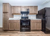 Thumbnail 6 of 35 - A kitchen with a black fridge and a black microwave on a counter.
