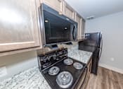 Thumbnail 7 of 35 - A black stove top oven with a microwave above it.