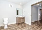 Thumbnail 21 of 35 - A white toilet sits in a bathroom with a wooden floor and a marble countertop.