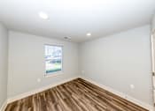 Thumbnail 15 of 35 - A room with wooden flooring and a window showing an outdoor view.