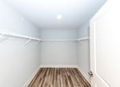 Thumbnail 20 of 35 - A white closet with a wooden floor and a door.