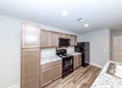 Thumbnail 3 of 35 - A kitchen with wooden cabinets and a black fridge.