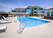 Thumbnail 12 of 19 - A pool with  lounge chairs and apartment buildings in the background