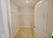 Thumbnail 15 of 24 - A small, empty closet with a carpeted floor and a white door.