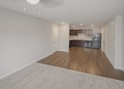 Thumbnail 2 of 24 - A spacious kitchen with wood floors and white walls.
