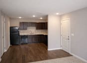 Thumbnail 3 of 24 - A kitchen with a black fridge and brown cabinets.