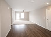 Thumbnail 6 of 24 - A room with wooden floors and white walls.