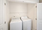 Thumbnail 8 of 24 - Two white washing machines in a small laundry room.