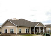 Thumbnail 2 of 25 - A house with a brown roof and beige siding with white trim.