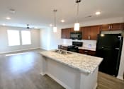 Thumbnail 12 of 25 - A kitchen with a granite countertop and black appliances.