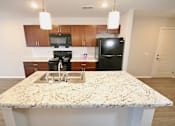 Thumbnail 13 of 25 - A kitchen with granite countertops and a black refrigerator.