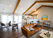 Thumbnail 2 of 14 - Clubhouse lounge area with a couch table and chairs and a kitchen in the background at Maple Tree Apartments in LaPorte, IN