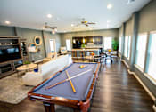 Thumbnail 6 of 25 - A pool table is in the middle of a room with a television and a couch.