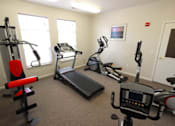 Thumbnail 11 of 15 - Fitness center with cardio equipment and a weight machine at Canterbury Apartments in Kalamazoo, Mi