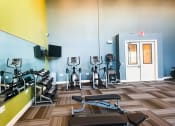Thumbnail 10 of 22 - The fitness center with ellipticals, mirror, and TV at The Lofts at Canterbury in Slidell, Louisiana