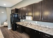 Thumbnail 7 of 25 - A kitchen with dark brown cabinets and a granite countertop.